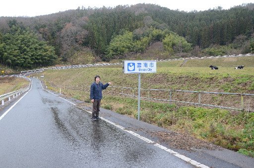 飛び地付近にある「雲南市」の標識前に立つ大石亘太さん＝島根県奥出雲町佐白から撮影
