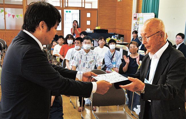記念式典で湊俊樹会長（左）から感謝状を受け取る坂本忠直さん＝江津市二宮町、青陵中学校