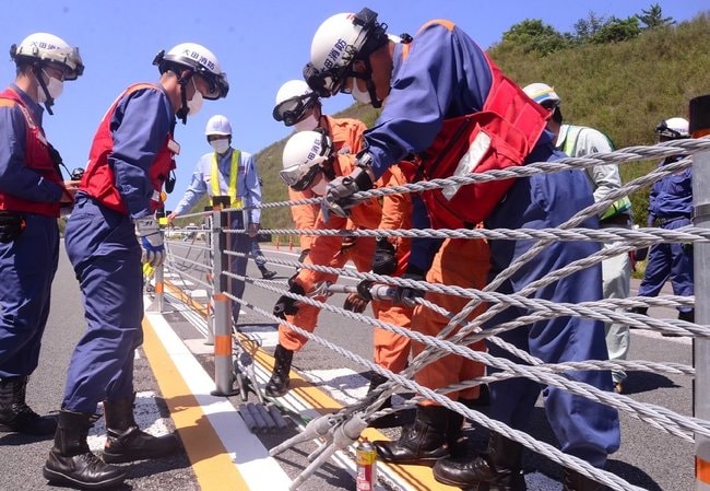 ワイヤロープ式防護柵の脱着訓練に臨む大田市消防本部の隊員たち＝２０２１年７月、大田市波根町の山陰道朝山・大田道路