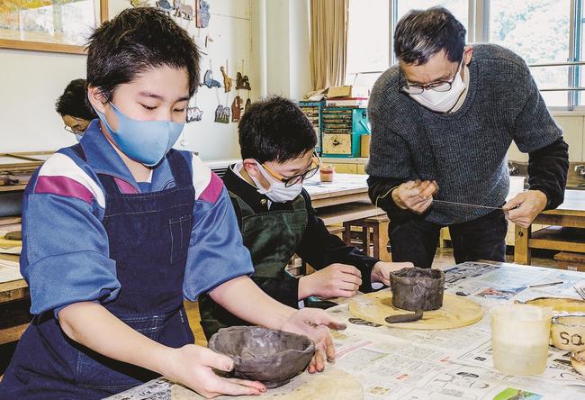 講師の永見克久さん（右）の手ほどきを受け、思い思いに陶芸作品を作る児童＝雲南市木次町西日登、市立西日登小学校
