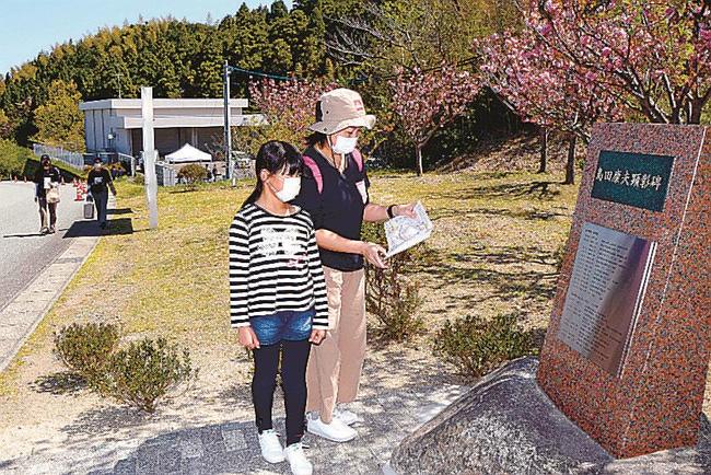 スタンプラリーの途中で故島田康夫さんの顕彰碑を眺める親子＝浜田市野原町