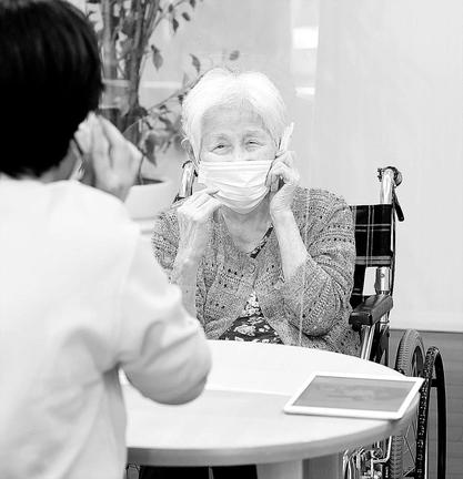 新型コロナウイルス禍で迎えた２度目の敬老の日、東京都文京区の介護付き有料老人ホーム「杜の癒しハウス文京関口」では、感染予防のためアクリル板越しに面会する家族の姿が見られた。白寿を迎えた溝口園さん（９９）は耳が遠いため、携帯電話を使って訪れた長女（６３）と楽しそうに話していた。今年４月から施設内で面会できるようになり、６月には周辺の散歩も可能になった。車いすを押しながら近所を一緒に巡った長女は「もどかしいけど、もうしばらくの我慢かな」と、家族が触れ合える日を楽しみにしていた＝２０日午後