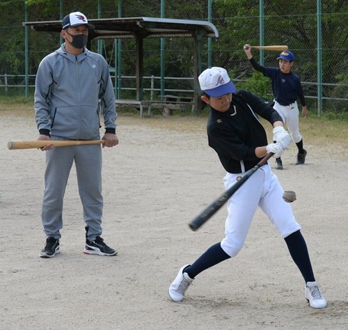塚田秀典監督（左）に指導を受けながら、打撃練習に取り組む部員たち＝松江市西津田９丁目、西津田運動公