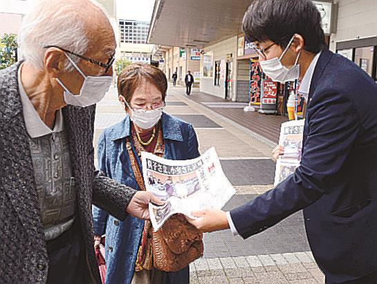号外を受け取る市民（左）＝出雲市駅北町、ＪＲ出雲市駅北口