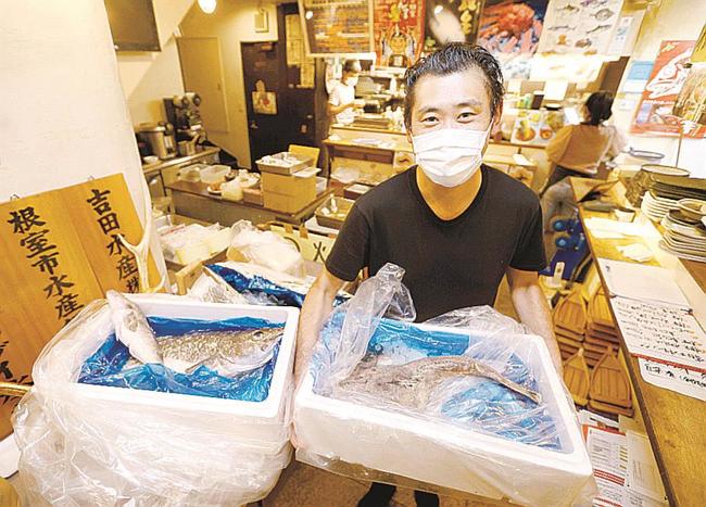 営業時間短縮要請の解除に向けて仕入れた魚を手にする「根室食堂」の店主平山徳治さん＝２４日夜、東京・新橋