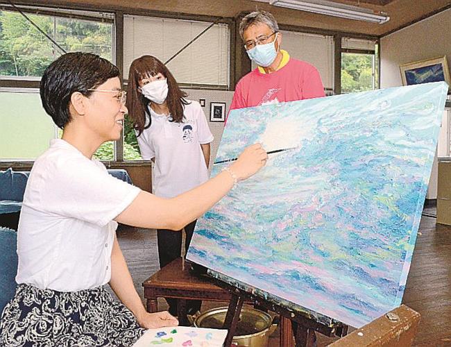 江府町役場旧庁舎で新作を描く志水朝さん（手前）＝鳥取県江府町江尾