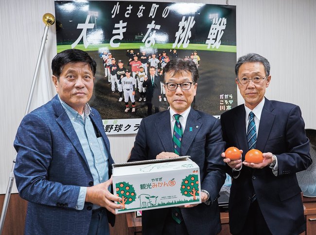 野坂一弥町長にミカンを手渡す佐伯勝美さん（左）＝島根県川本町川本、町役場