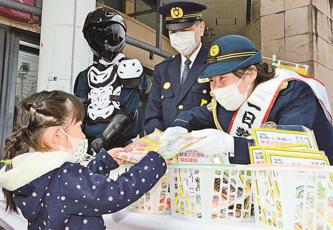 女児に啓発グッズを手渡し歳末の交通安全などを呼び掛ける入江聖奈選手（右）＝米子市末広町、イオン米子駅前店前