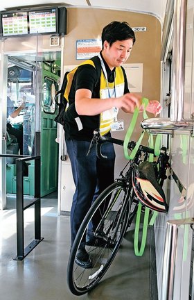 サイクルトレインの実証実験で車内に自転車を固定する参加者＝２０２４年７月、米子市弥生町、ＪＲ米子駅