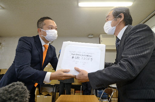 境港市選挙管理委員会の三代智委員長に署名簿を手渡す黒目伸一郎会長（左）＝境港市上道町、市役所