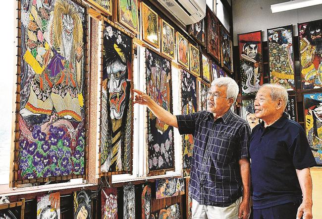駅舎内の一室で来場者に作品を紹介する山崎忠正さん（左）＝江津市桜江町川戸、旧ＪＲ三江線川戸駅