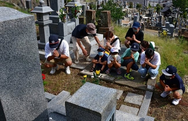 先祖の墓に手を合わせる家族＝２０２２年８月、松江市内