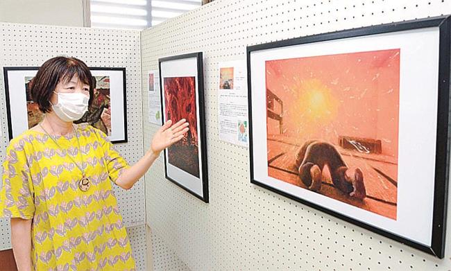 高校生が描いた被爆体験の絵を紹介する向田真由美支部長＝安来市安来町、市立図書館