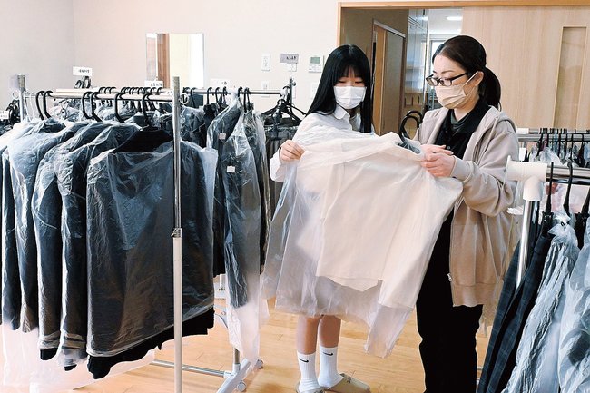 リユース制服を選ぶ親子=松江市大輪町、大輪子どもハウス