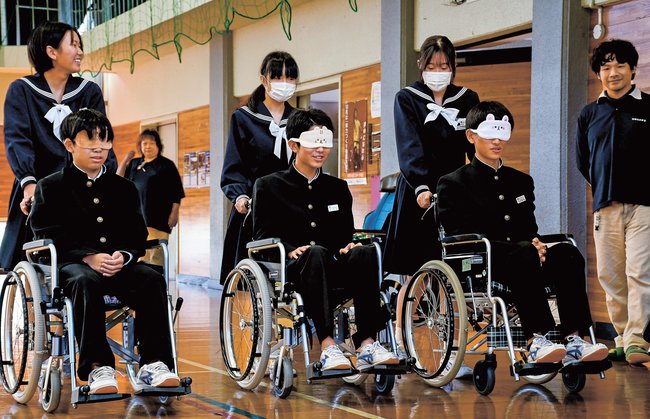 目隠しした状態で車いすに乗る体験をする生徒＝浜田市金城町下来原、金城中学校