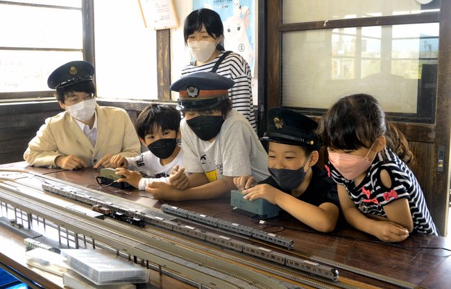 鳥取大生（左）の指導を受けながら、鉄道模型を動かす子どもたち＝鳥取県大山町西坪、ＪＲ御来屋駅