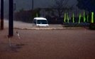 大雨の影響で冠水した道路を走る車＝１３日午前１０時４９分、鳥取市福部町内