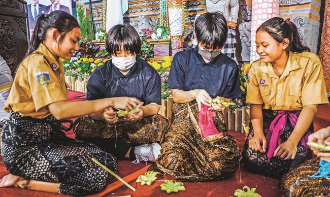 マス村の中学生（両端）に教わりながら、チャナンを作る美郷町の中学生＝インドネシア・バリ島