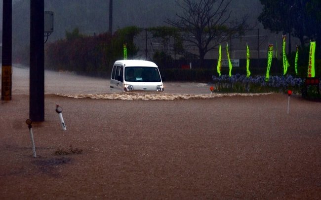 大雨の影響で冠水した道路を走る車＝１３日午前１０時４９分、鳥取市福部町内