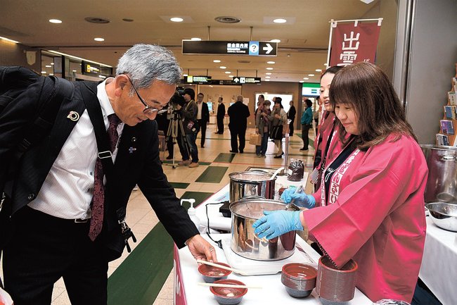 ぜんざいを求める搭乗客(左)=出雲市斐川町沖洲、出雲空港