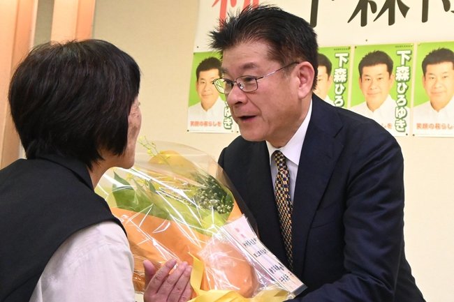 支持者から花束を受け取る下森博之氏（右）＝島根県津和野町枕瀬、ＪＡしまねグリーンセンターひまわり