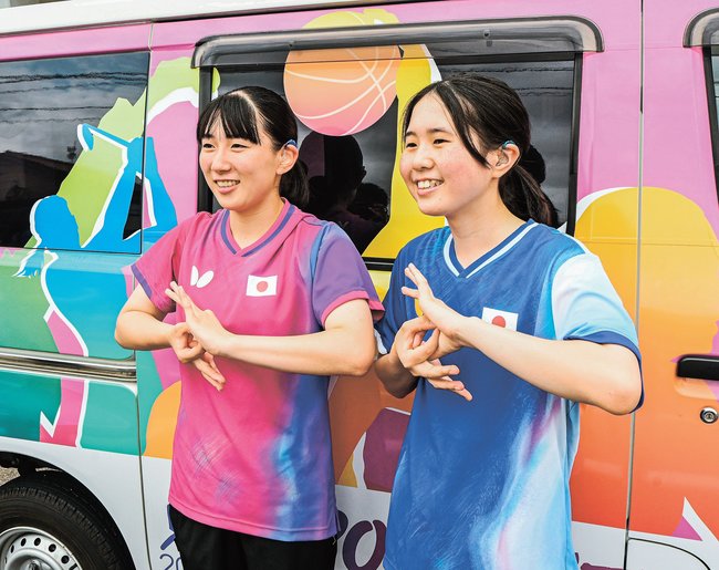 デフリンピックを表す手話をする山田萌心選手（左）と佐々岡希花選手＝益田市常盤町、市役所前