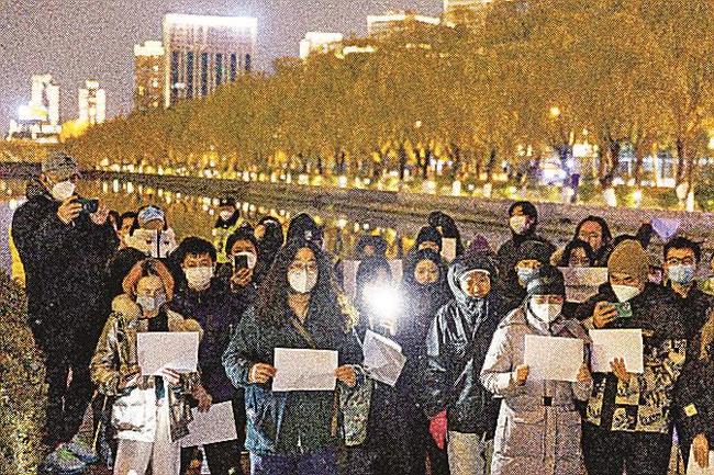 北京市内で中国の「ゼロコロナ」政策に反対し、当局への抗議を意味する白い紙を手にする人たち＝２７日（ロイター＝共同）