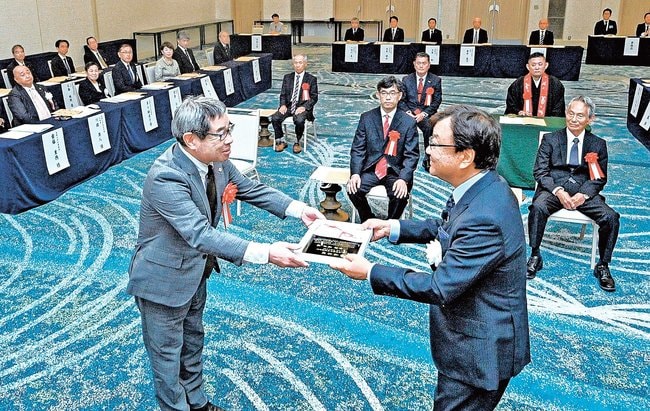 松尾倫男社長（右）から表彰状を受け取る金津義彦さん＝松江市千鳥町、ホテル一畑