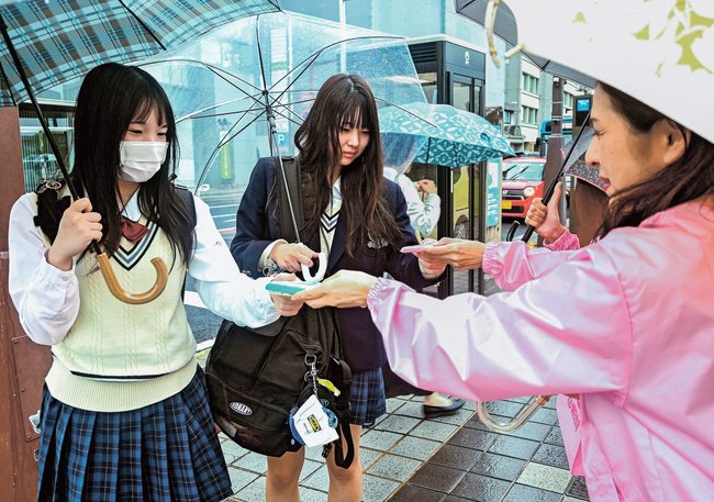 乳がん検診の受診を呼びかけるチラシを受け取る高校生＝松江市殿町