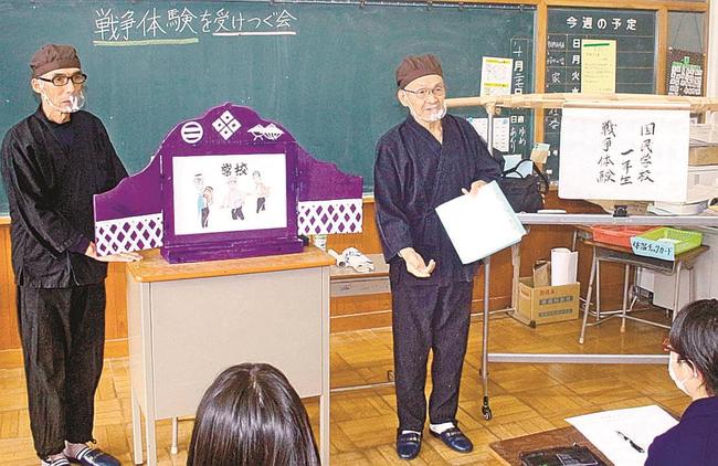 児童たちに戦争体験の紙芝居を披露する田中豊司さん（右）と高野淳さん＝島根県津和野町森村、津和野小学校