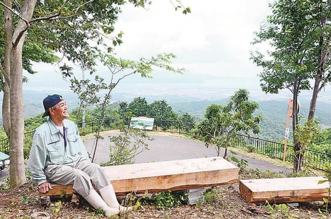 新しく設置したベンチに座る三島一成会長＝松江市東出雲町揖屋