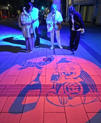 こなき爺の図柄の妖怪影絵に見入る観光客＝境港市松ケ枝町、水木しげるロード