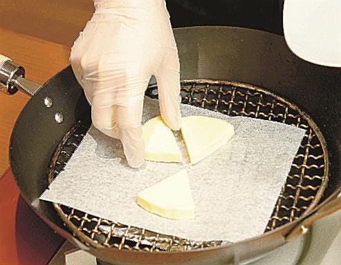 チーズがくっつかないように網の上にクッキングシートをのせる＝東京都文京区