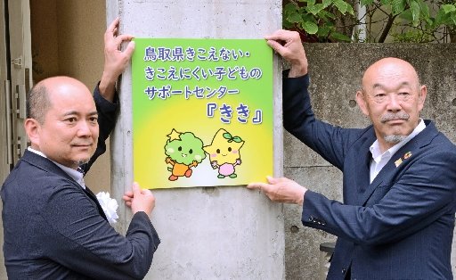 サポートセンターの看板を掛ける石橋大吾センター長(左)=鳥取市桜谷