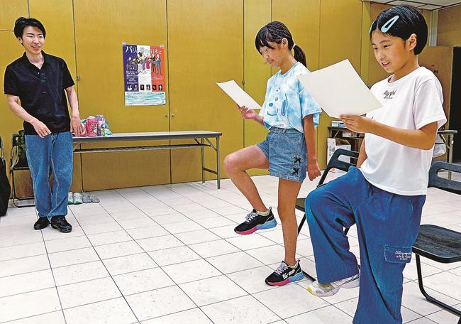 竹内大樹さん（左）に教わりながら、片足を上げて台本を読む参加者＝島根県川本町川本、悠邑ふるさと会館