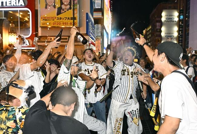 阪神がセ・リーグ優勝を決め、大阪・ミナミでビールかけをする人たち＝１４日夜