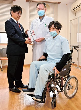 目録を受け取る新田一豊理事長（中央）ら＝米子市中島２丁目、昌生会デイケア新田