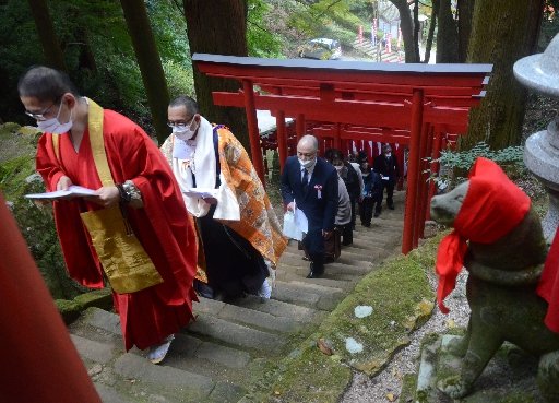 新しい鳥居（手前３基）の完成を祝い、渡り初めをする清水谷善暁住職（左から２人目）ら関係者＝安来市清水町、清水稲荷社