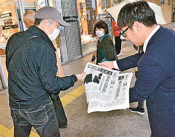 細田博之氏の訃報を伝える号外を手に取る人＝松江市朝日町、ＪＲ松江駅