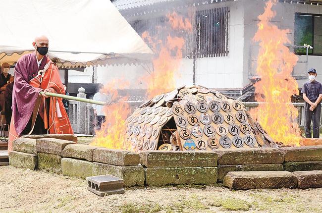 積まれた絵馬に火をつける飯塚大幸管長（左）＝出雲市小境町、一畑薬師