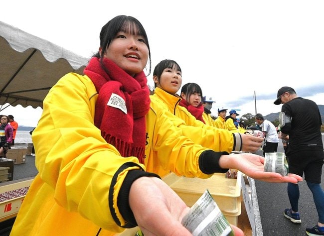 ランナーに軽食を手渡すボランティア（昨年の大会より）