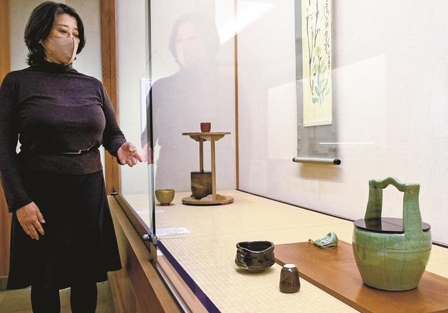 青磁手桶水指（右）と春にまつわる茶器を紹介する佐々木杏里学芸員＝出雲市大社町杵築西、手銭美術館