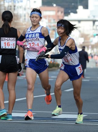 平田の４区田辺心（左）からたすきを受け、駆け出す５区本田琴弓‖西大路下立売、第４中継所