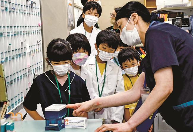 病院内の薬局で薬剤師の仕事について教わる参加者＝島根県吉賀町六日市、よしか病院