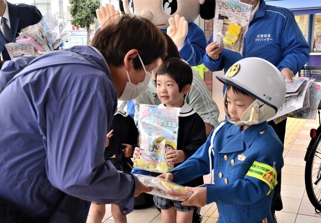 買い物客（左）に啓発グッズの入った袋を手渡す園児＝浜田市港町、ゆめタウン浜田