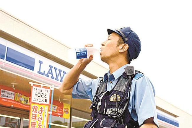 コンビニで購入した商品で水分補給する警察官＝松江市比津町