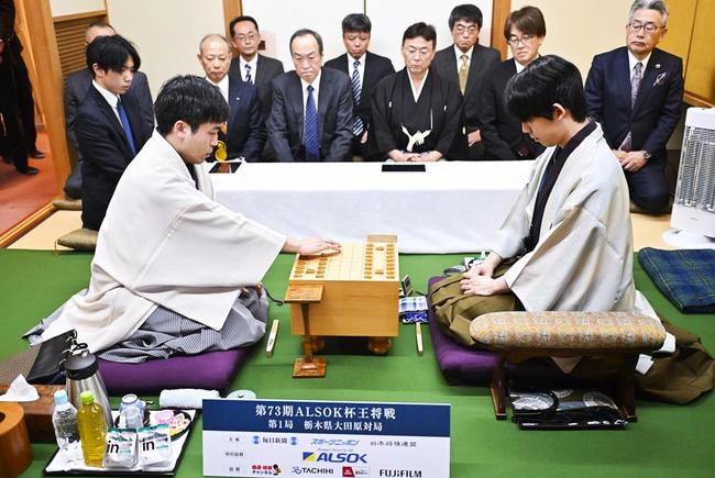 第73期王将戦７番勝負の第１局で、初手を指す菅井竜也八段。右は藤井聡太王将＝７日午前、栃木県大田原市（代表撮影）