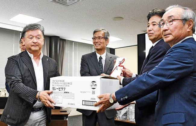 長期保存レトルト食品を寄贈する笠浩一郎代表（左）＝出雲市今市町、市役所