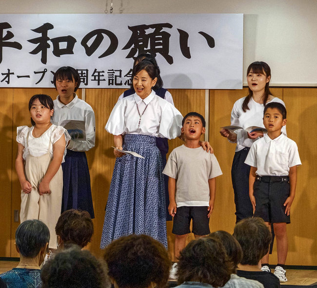 三刀屋小学校の児童らと「折り鶴」を歌う吉永小百合さん(中央)=雲南市三刀屋町三刀屋、市三刀屋交流センター(雲南市提供)