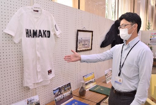 浜田高校野球部のユニフォームや甲子園出場時の記念写真を紹介する河野洋介さん＝浜田市殿町、日本海信用金庫